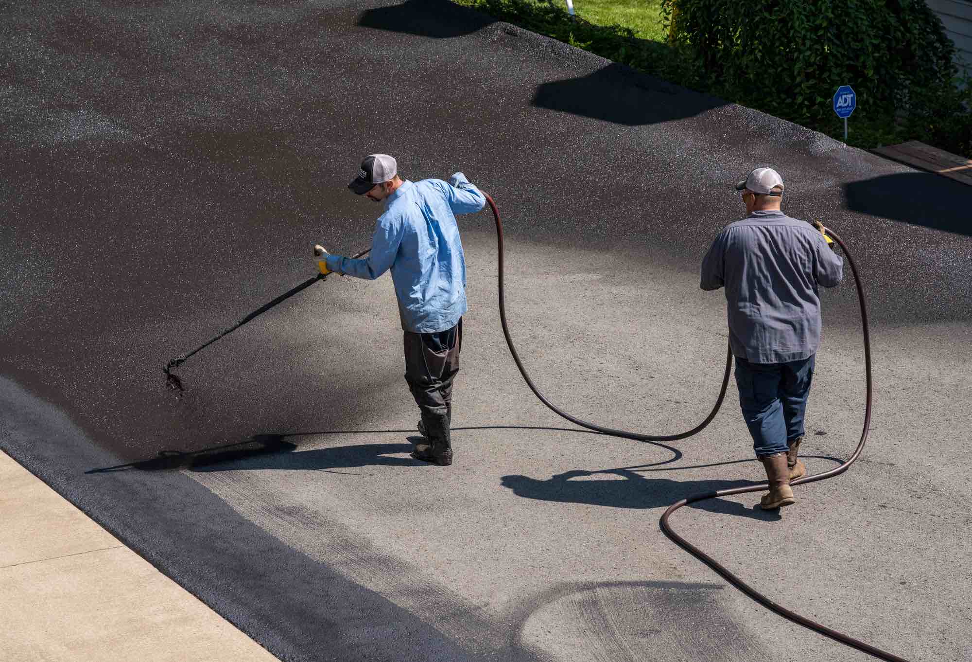 Crew applying sealcoat to a driveway